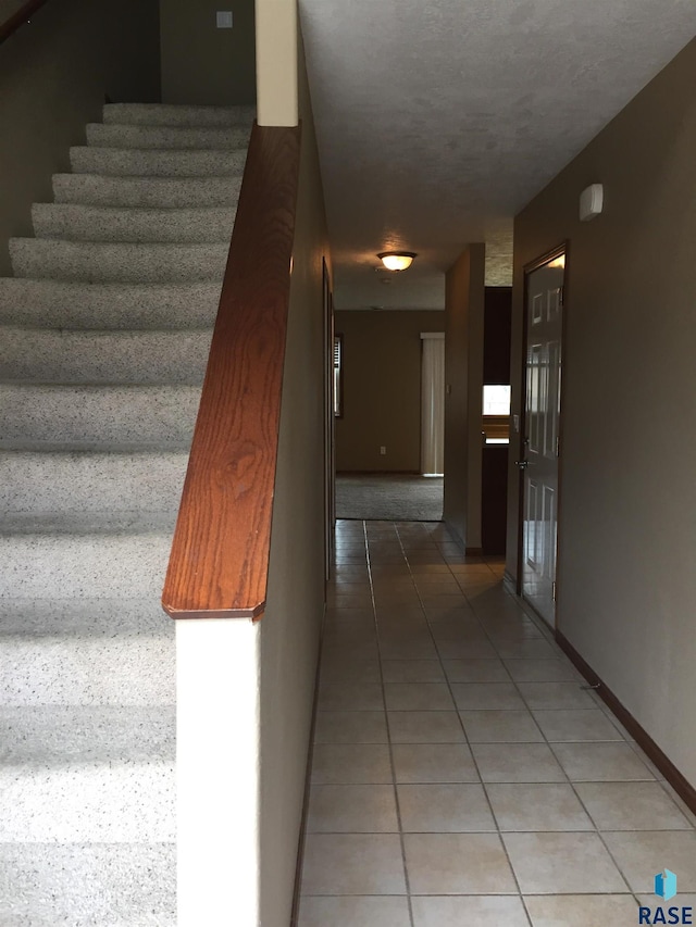 interior space with stairway, light tile patterned flooring, and baseboards