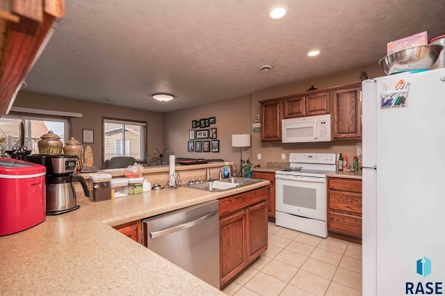 kitchen featuring light countertops, light tile patterned floors, white appliances, a textured ceiling, and a sink