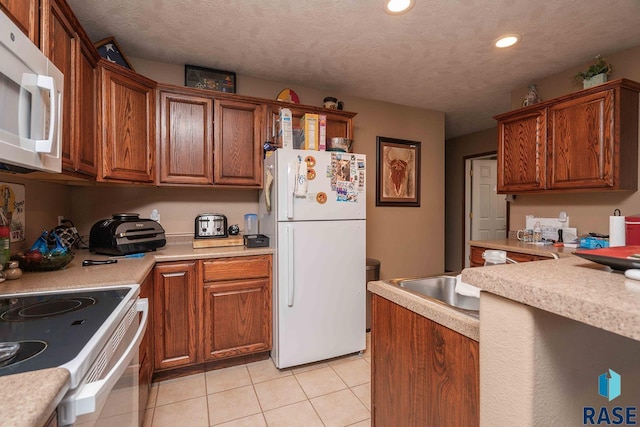 kitchen featuring white appliances, light tile patterned flooring, brown cabinetry, and light countertops