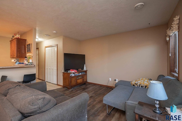 living room with baseboards, a textured ceiling, and wood finished floors