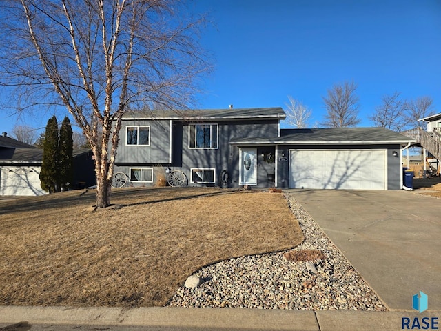 split level home featuring an attached garage, concrete driveway, and a front lawn