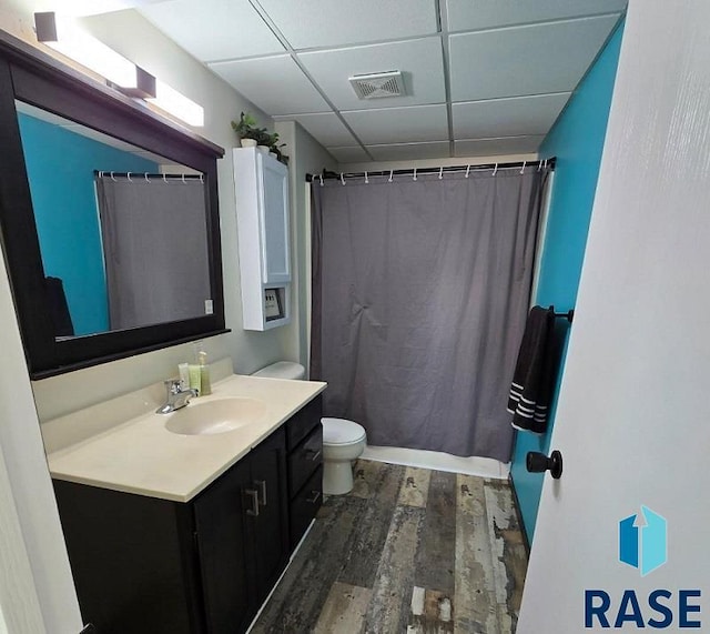 bathroom with visible vents, toilet, a drop ceiling, wood finished floors, and vanity