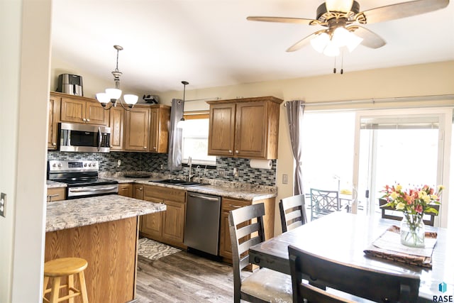 kitchen with decorative backsplash, brown cabinetry, appliances with stainless steel finishes, and a sink