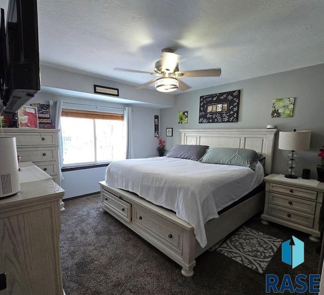 bedroom with a ceiling fan, dark carpet, and a textured ceiling