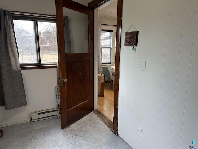 corridor with marble finish floor and a baseboard radiator