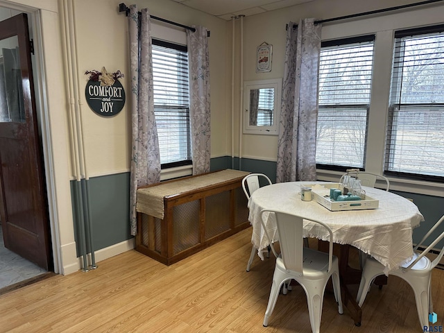 dining room featuring baseboards, light wood-style flooring, and radiator heating unit