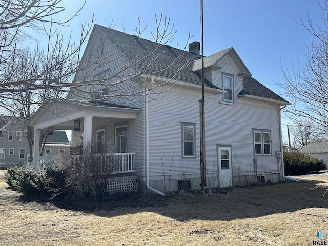 view of side of home featuring a shingled roof, a porch, and a chimney