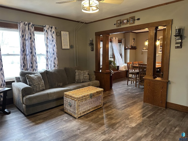 living room featuring wood finished floors, baseboards, decorative columns, ornamental molding, and ceiling fan