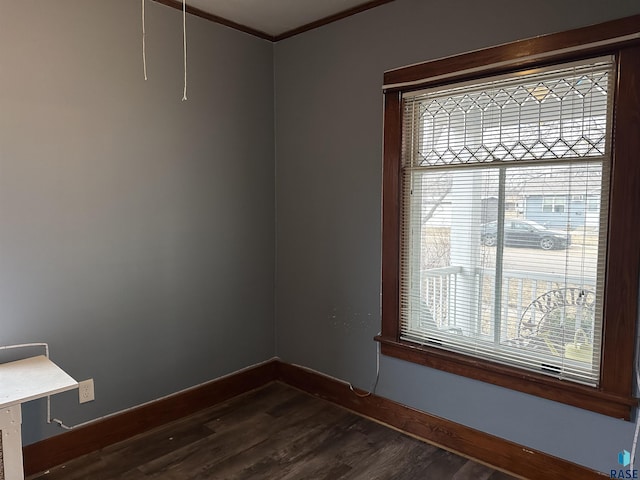 spare room featuring baseboards, dark wood finished floors, and crown molding