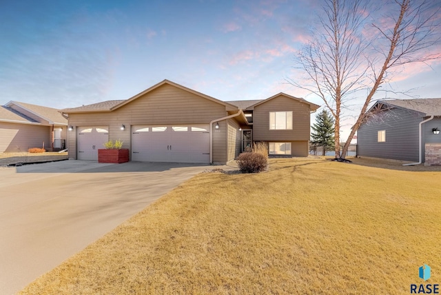 view of front facade with a front yard, concrete driveway, and an attached garage