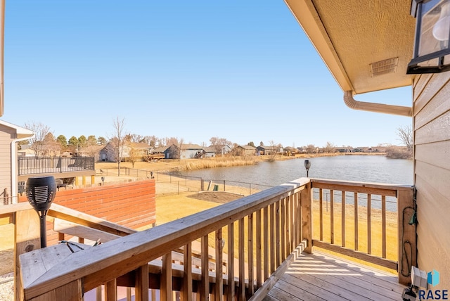 wooden terrace featuring visible vents, a water view, and fence