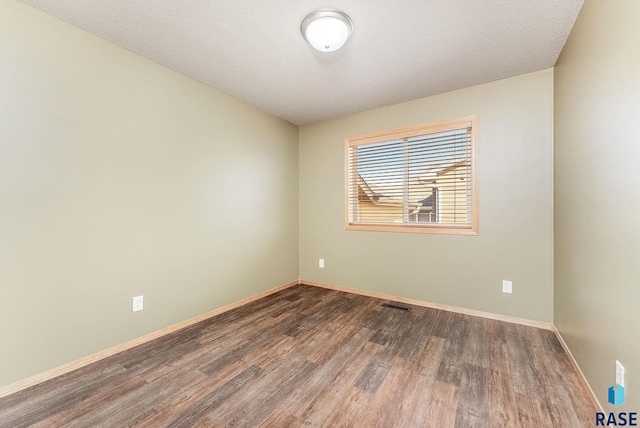 unfurnished room featuring visible vents, a textured ceiling, baseboards, and wood finished floors