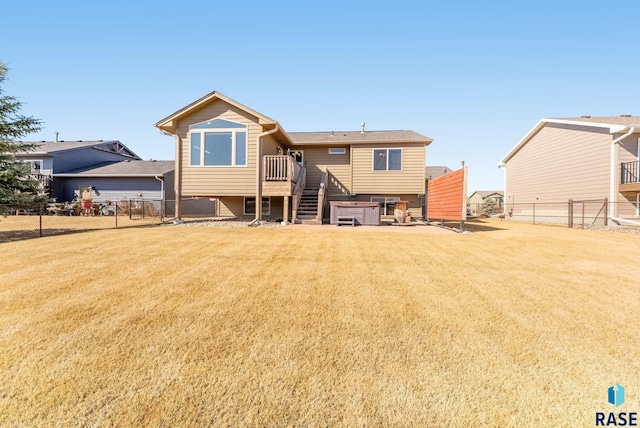 rear view of property featuring stairs, a yard, a fenced backyard, and a hot tub