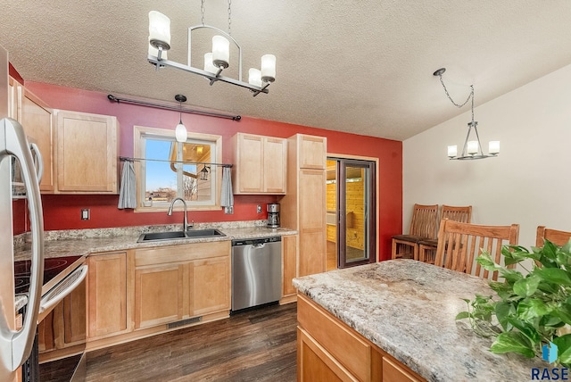 kitchen with a sink, light brown cabinetry, appliances with stainless steel finishes, an inviting chandelier, and dark wood-style flooring