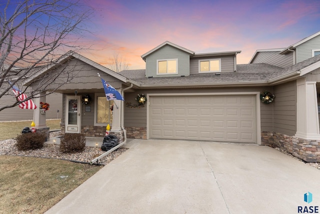 view of front facade featuring a garage, stone siding, roof with shingles, and driveway