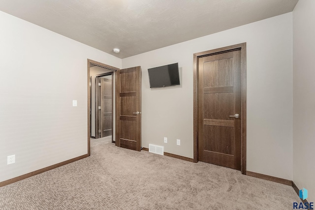 unfurnished bedroom featuring baseboards, carpet floors, and visible vents