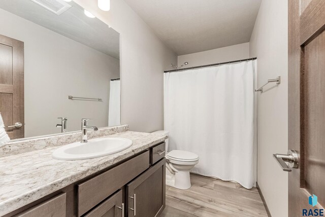full bathroom with visible vents, toilet, wood finished floors, and vanity