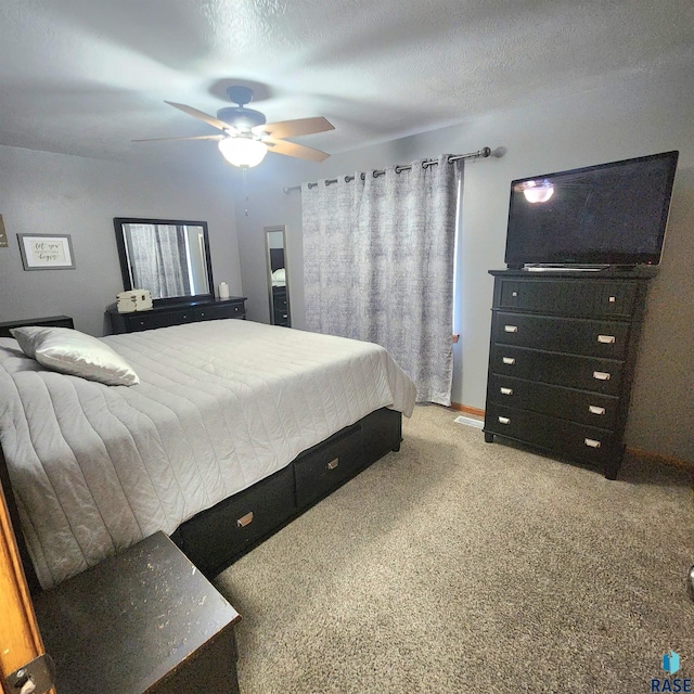 bedroom featuring light carpet, a textured ceiling, and a ceiling fan