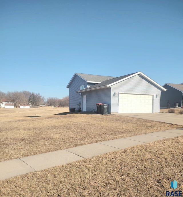 view of side of property featuring an attached garage, a lawn, and driveway