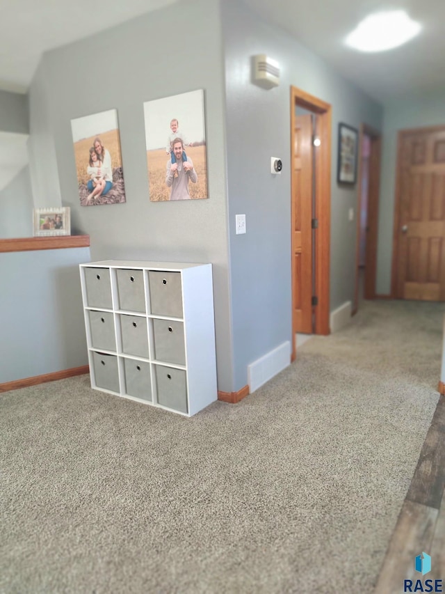 hall featuring visible vents, baseboards, and carpet floors