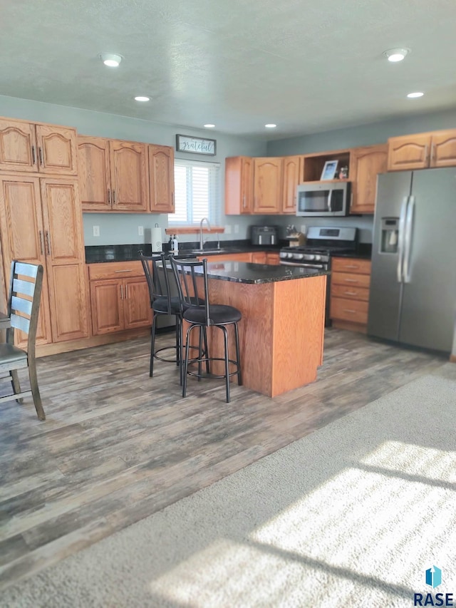 kitchen with a breakfast bar area, recessed lighting, a sink, stainless steel appliances, and a center island