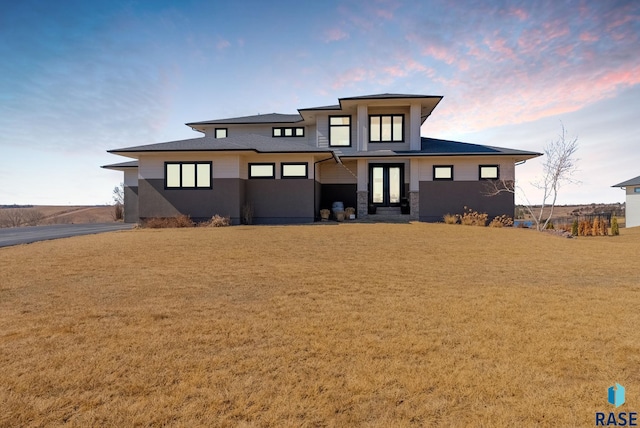 back of house with stone siding, a lawn, and french doors