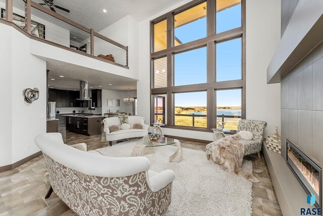 living area with a glass covered fireplace, a high ceiling, baseboards, and a chandelier