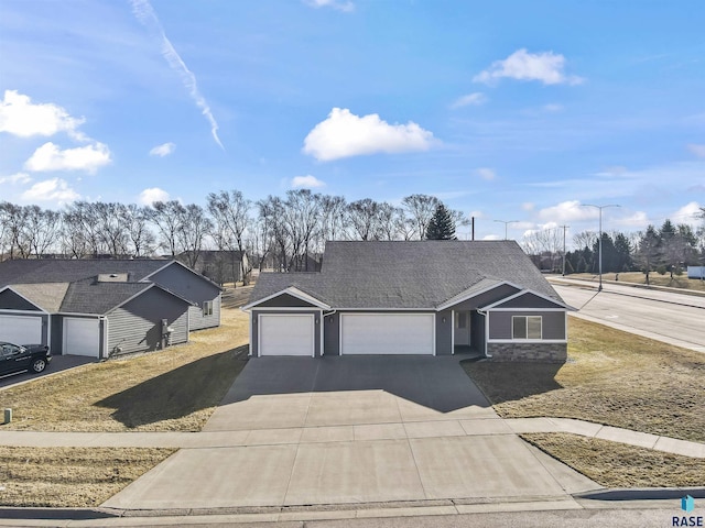 view of front facade featuring an attached garage, stone siding, driveway, and roof with shingles