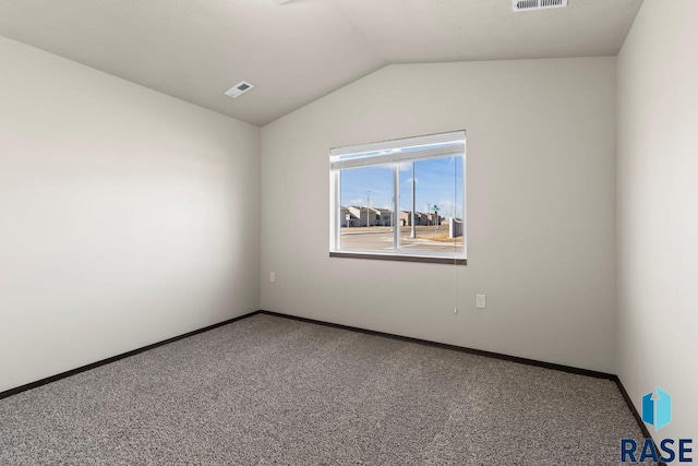 carpeted spare room featuring lofted ceiling, baseboards, and visible vents