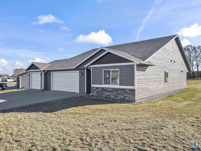 ranch-style home featuring a garage, concrete driveway, a front yard, and a shingled roof
