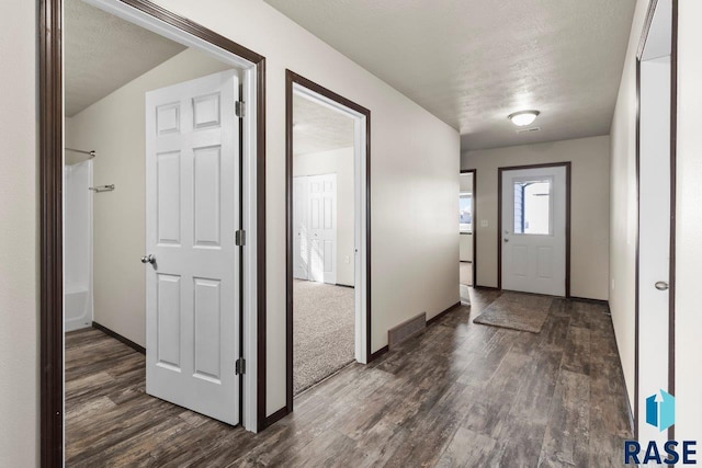 foyer entrance featuring baseboards, a textured ceiling, and dark wood finished floors