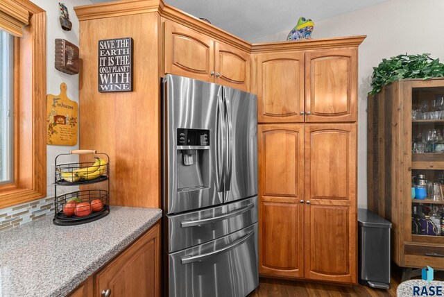 kitchen with backsplash, brown cabinets, dark wood finished floors, and stainless steel fridge with ice dispenser
