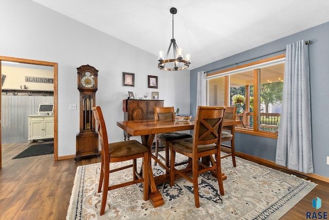 dining room with a notable chandelier, baseboards, lofted ceiling, and wood finished floors
