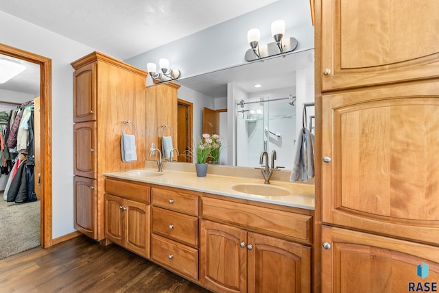 full bath with double vanity, wood finished floors, a stall shower, and a sink
