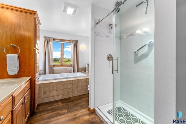 bathroom with a shower stall, vanity, a garden tub, and wood finished floors