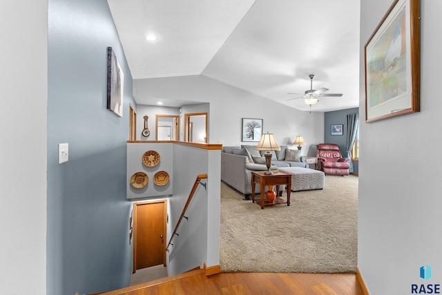 carpeted living room featuring lofted ceiling, wood finished floors, baseboards, and ceiling fan