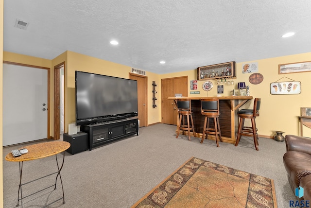 carpeted living area with recessed lighting, visible vents, a textured ceiling, and a dry bar