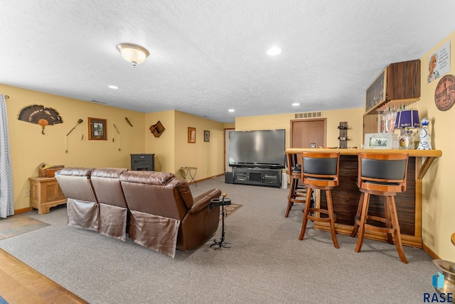 living area featuring a bar, recessed lighting, visible vents, and a textured ceiling