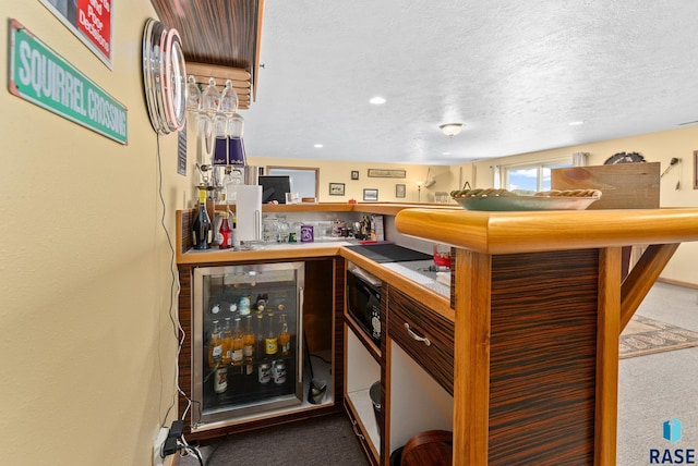 bar featuring wine cooler, a textured ceiling, indoor wet bar, and carpet