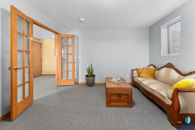 carpeted living area featuring visible vents, baseboards, and a textured ceiling