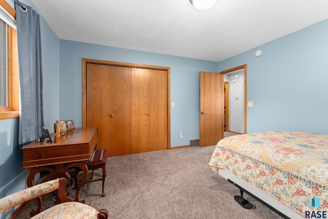 carpeted bedroom featuring a closet, a textured ceiling, and baseboards