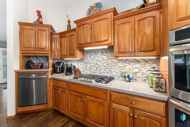 kitchen featuring dark wood-style floors, brown cabinets, stainless steel appliances, and tasteful backsplash
