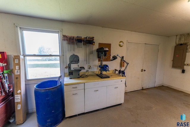 interior space with electric panel, concrete floors, white cabinetry, and light countertops