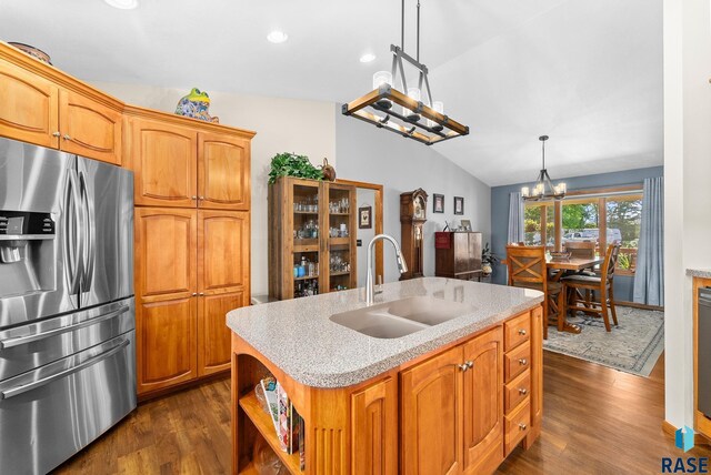 kitchen featuring dark wood-type flooring, vaulted ceiling, a notable chandelier, stainless steel fridge, and a sink