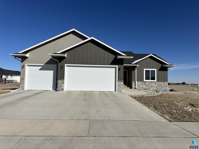view of front facade with stone siding, board and batten siding, concrete driveway, and an attached garage