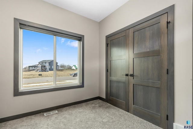 unfurnished bedroom with carpet, baseboards, visible vents, and a closet