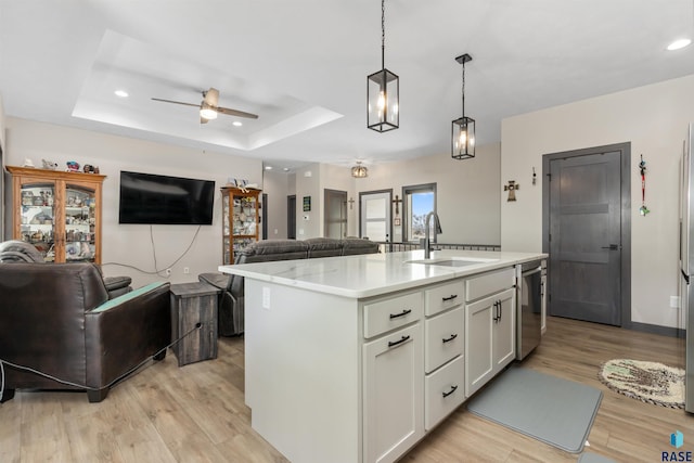 kitchen with ceiling fan, a raised ceiling, open floor plan, and a sink