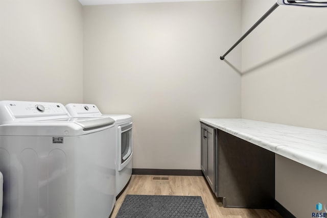 laundry room with cabinet space, washing machine and dryer, baseboards, and light wood-style floors