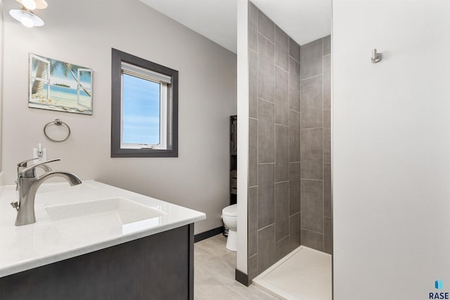 bathroom featuring double vanity, a tile shower, a sink, tile patterned flooring, and toilet