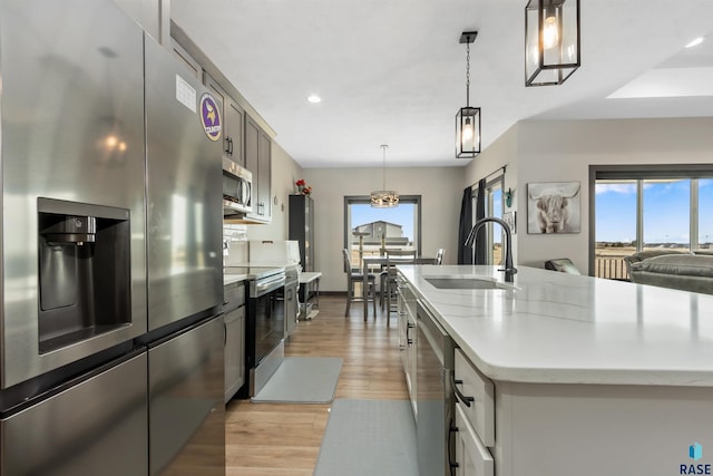 kitchen featuring a sink, stainless steel appliances, light wood-type flooring, and a wealth of natural light